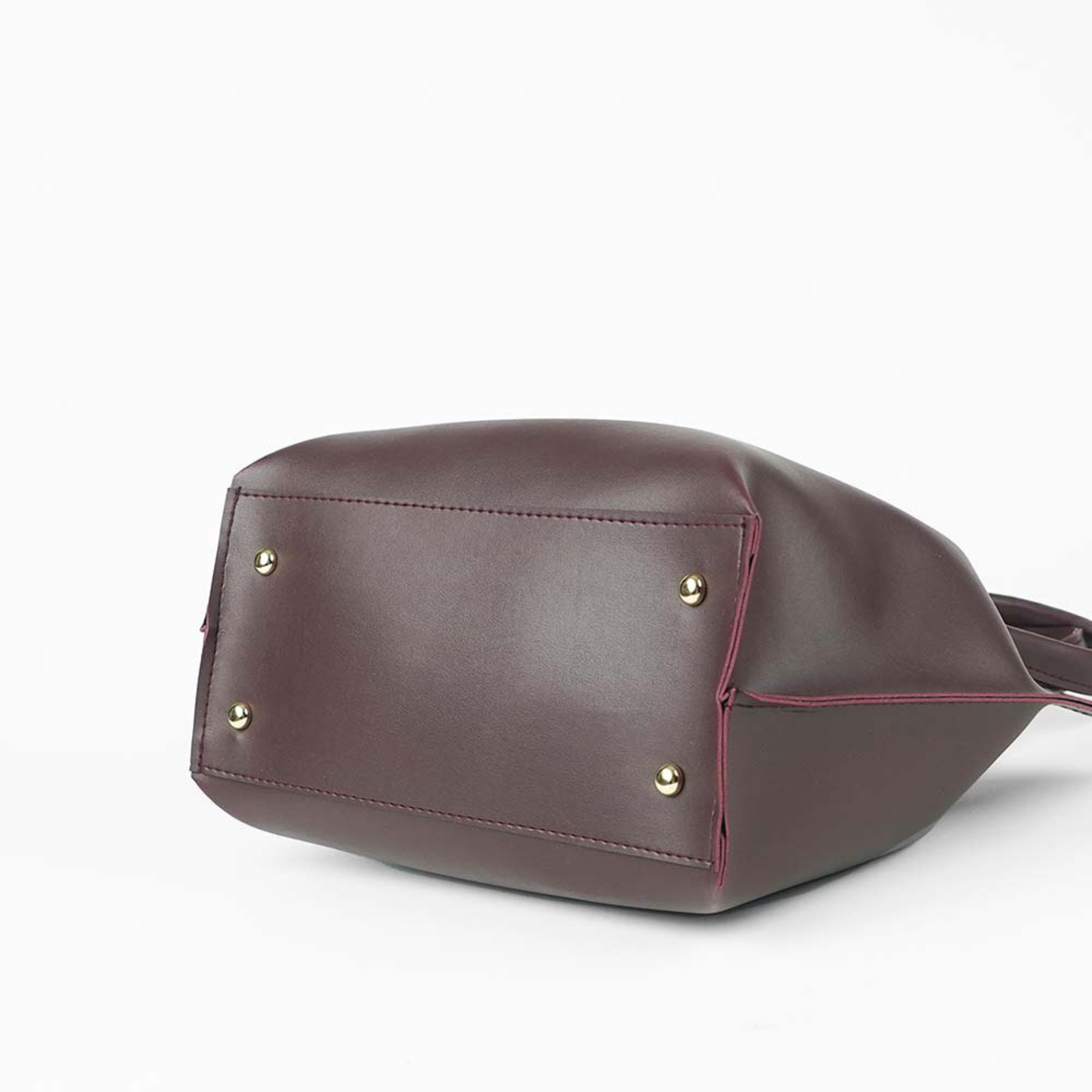maroon leather handbag with gold studs on a white background
