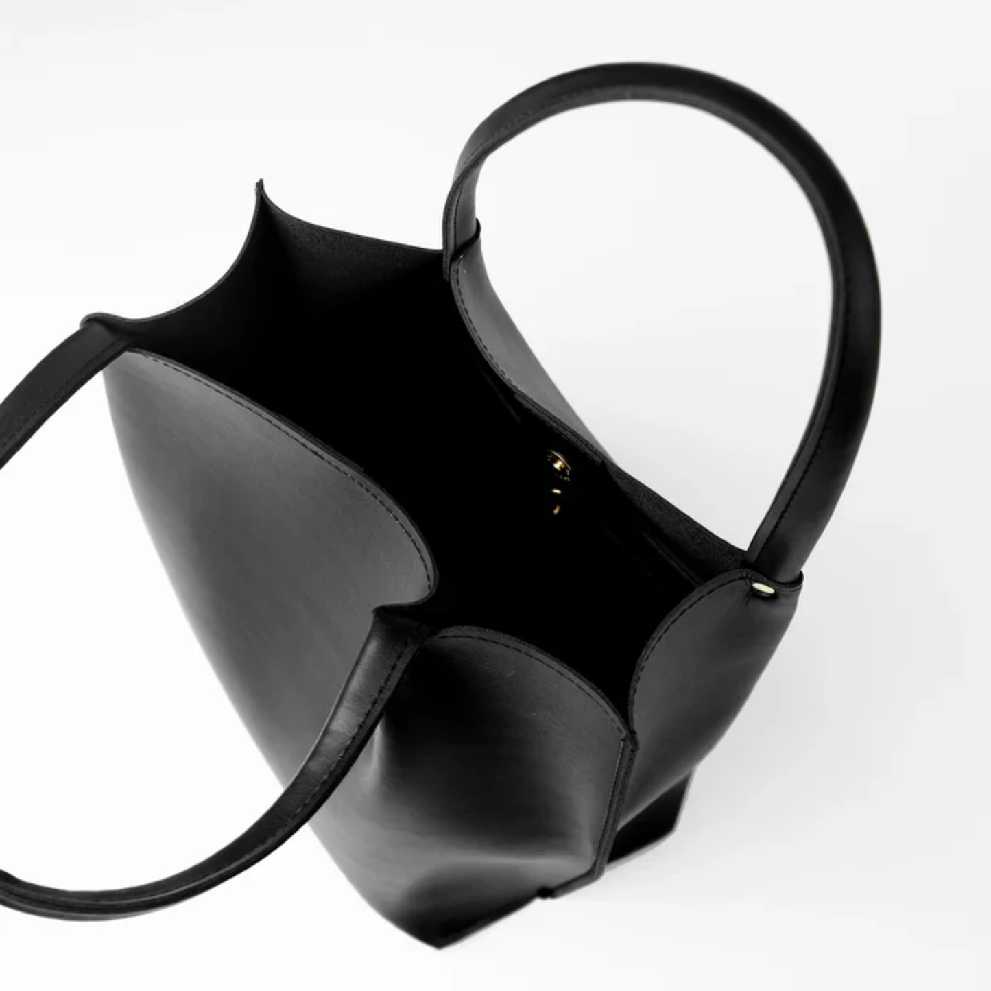 Black handmade leather tote bag with long handles on a white background