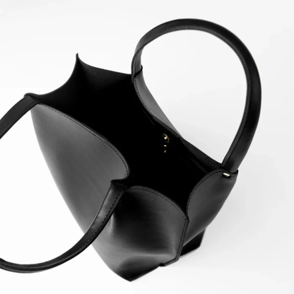 Black handmade leather tote bag with long handles on a white background