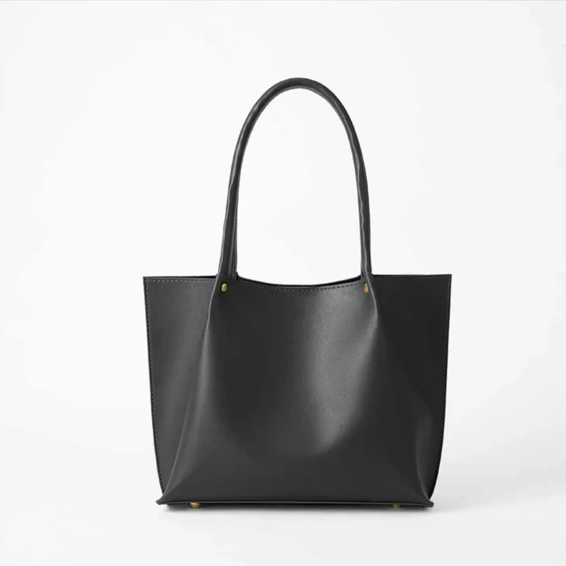 Black leather tote bag with long handles on a white background.