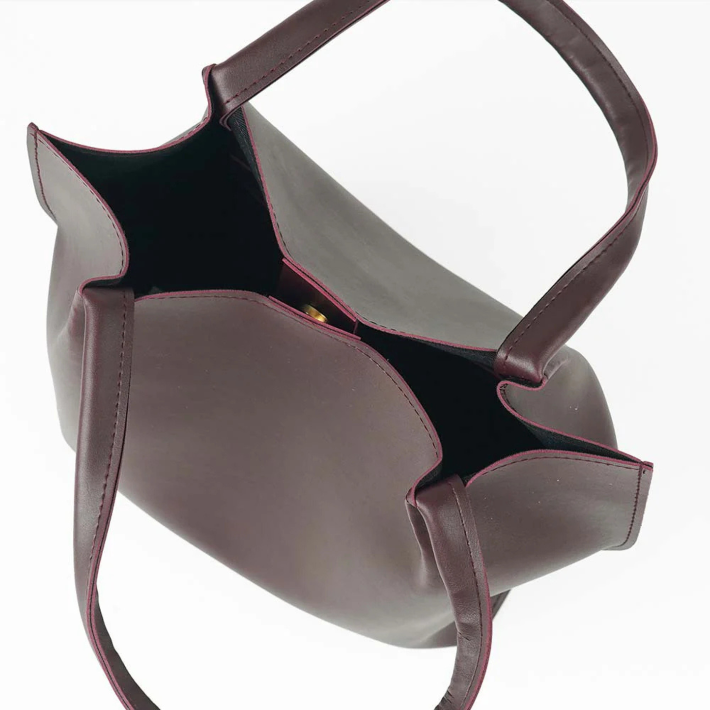 maroon leather handbag with a shoulder strap on a white background