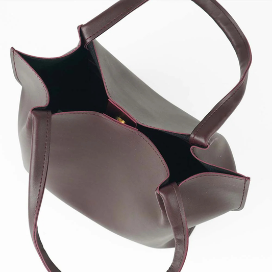 maroon leather handbag with a shoulder strap on a white background